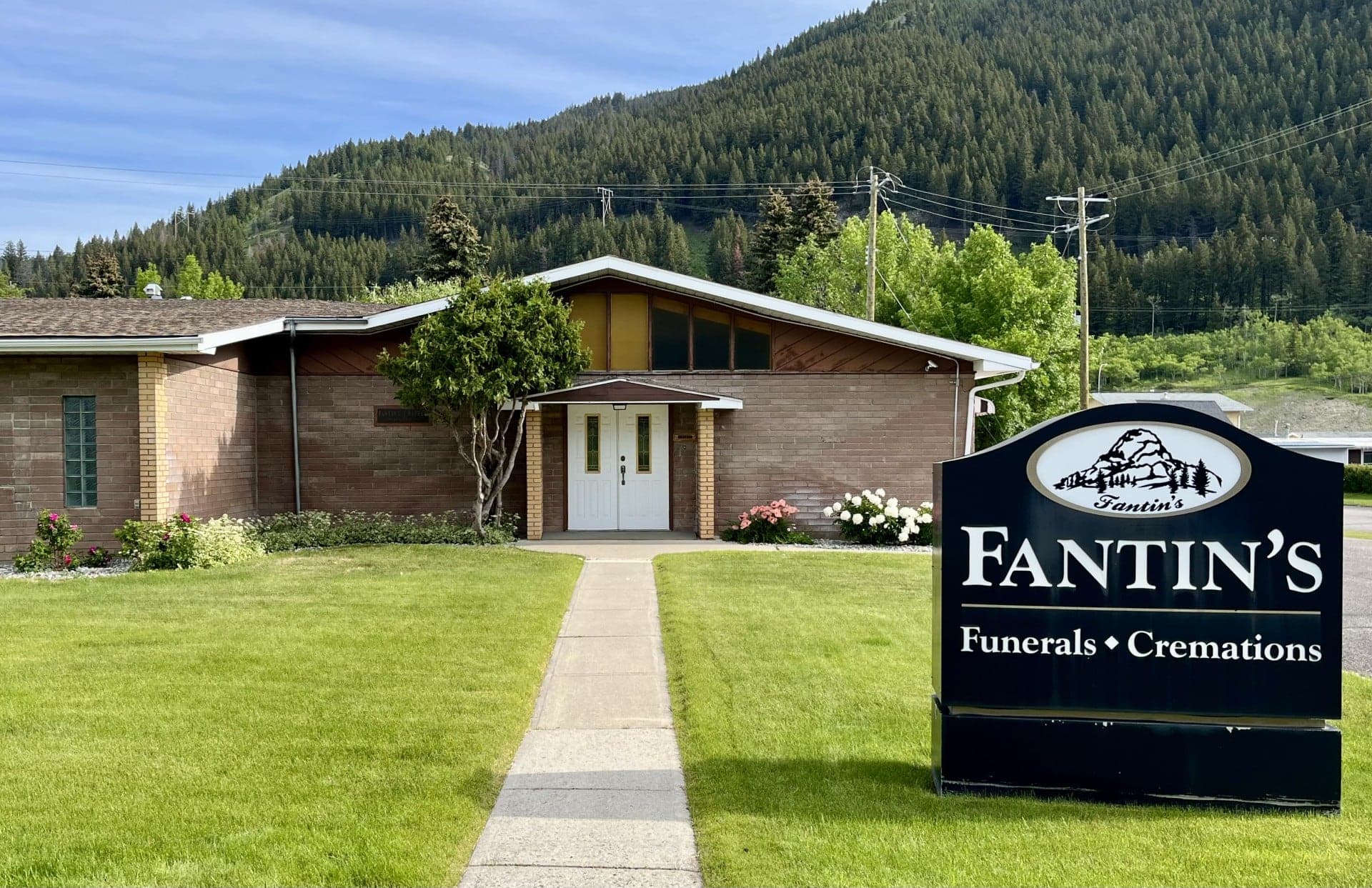 The front entrance of Fantin's Funeral Chapel in Blairmore: a path across the lawn to white double doors, beside the Fantin's Funerals & Cremations sign