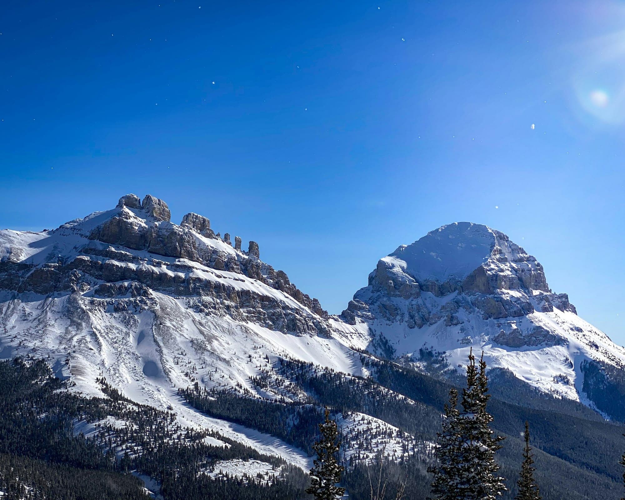 Snow-covered Crowsnest Mountain and its neighbouring peaks under a clear blue winter sky
