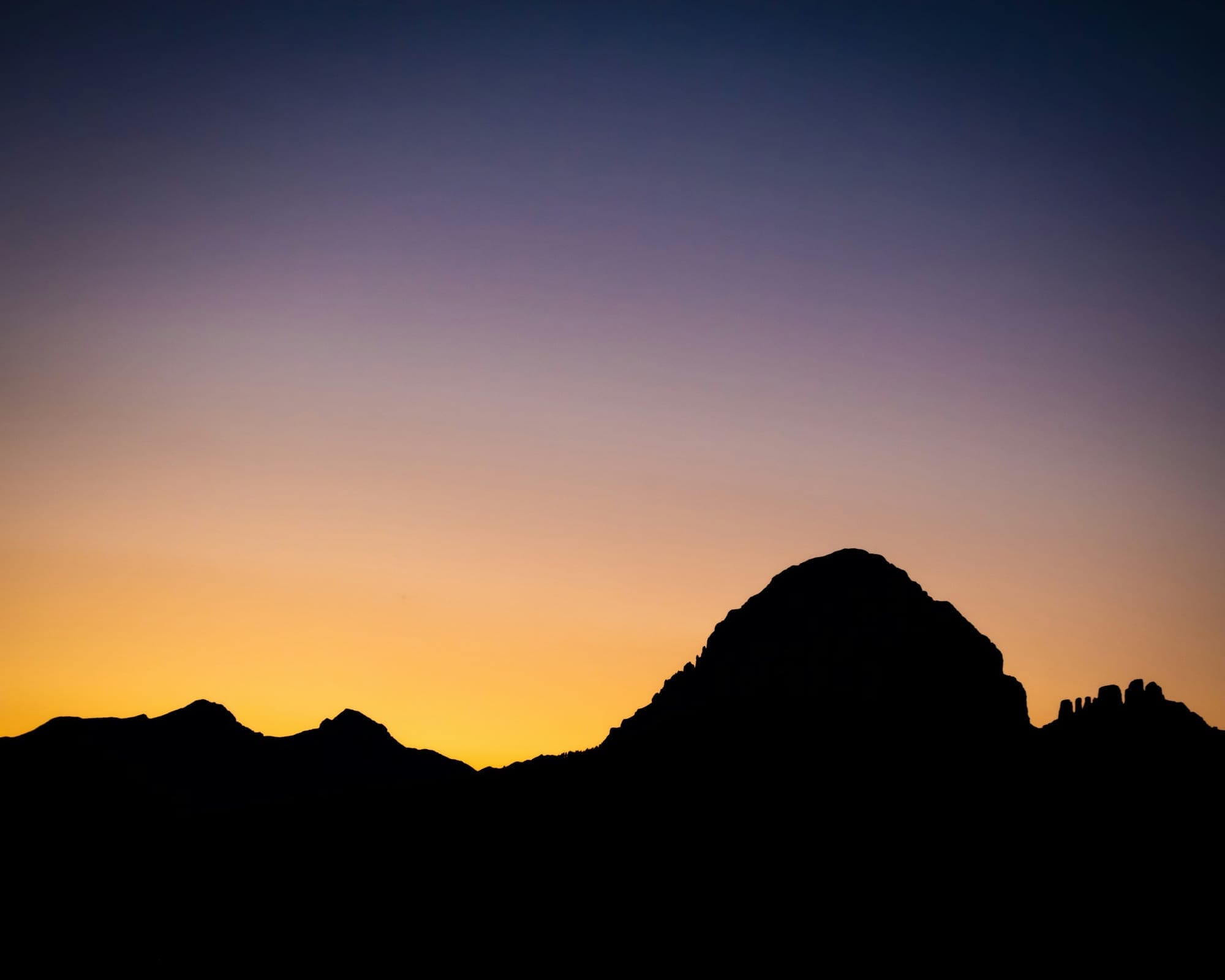 Crowsnest Mountain and the Seven Sisters in silhouette against an orange dusk sky